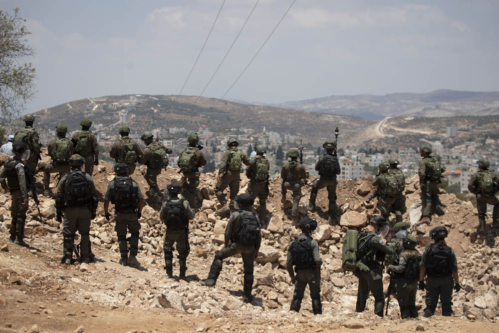 חיילים ושוטרי מג״ב עומדים על תלולית העפר שהקים הצבא כדי למנוע גישה לאזור מאחז שהקימו מתנחלים באדמות העירייה עסירה א-שמאלייה, 10 ביולי 2020 (צילום: אורן זיו)